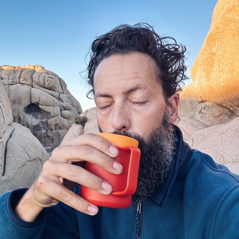 Kristian Kruse drinking coffee outdoors among desert rock formations.